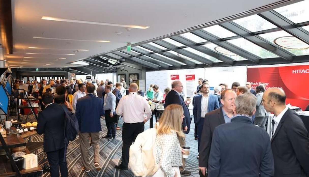 Attendees networking in a skylit expo hall at the SMR & Advanced Reactor conference, with sponsor booths and coffee stations.