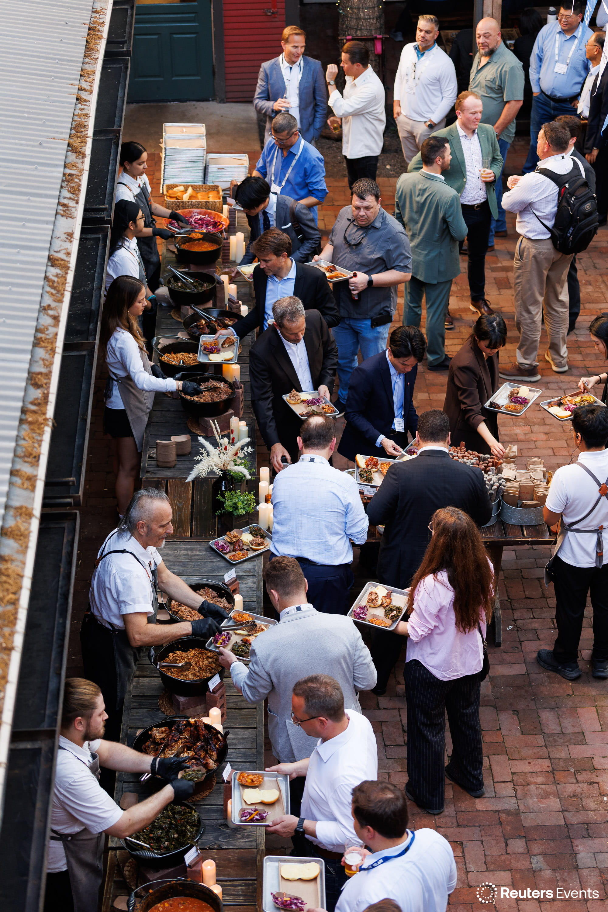 Overhead view of conference attendees at an outdoor buffet served by chefs