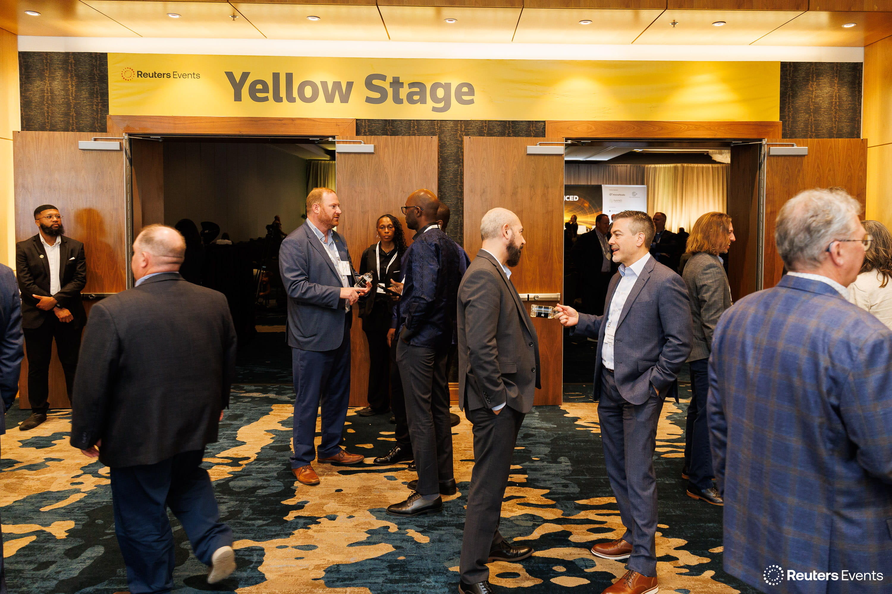 Attendees networking in pairs outside the Reuters Events Yellow Stage