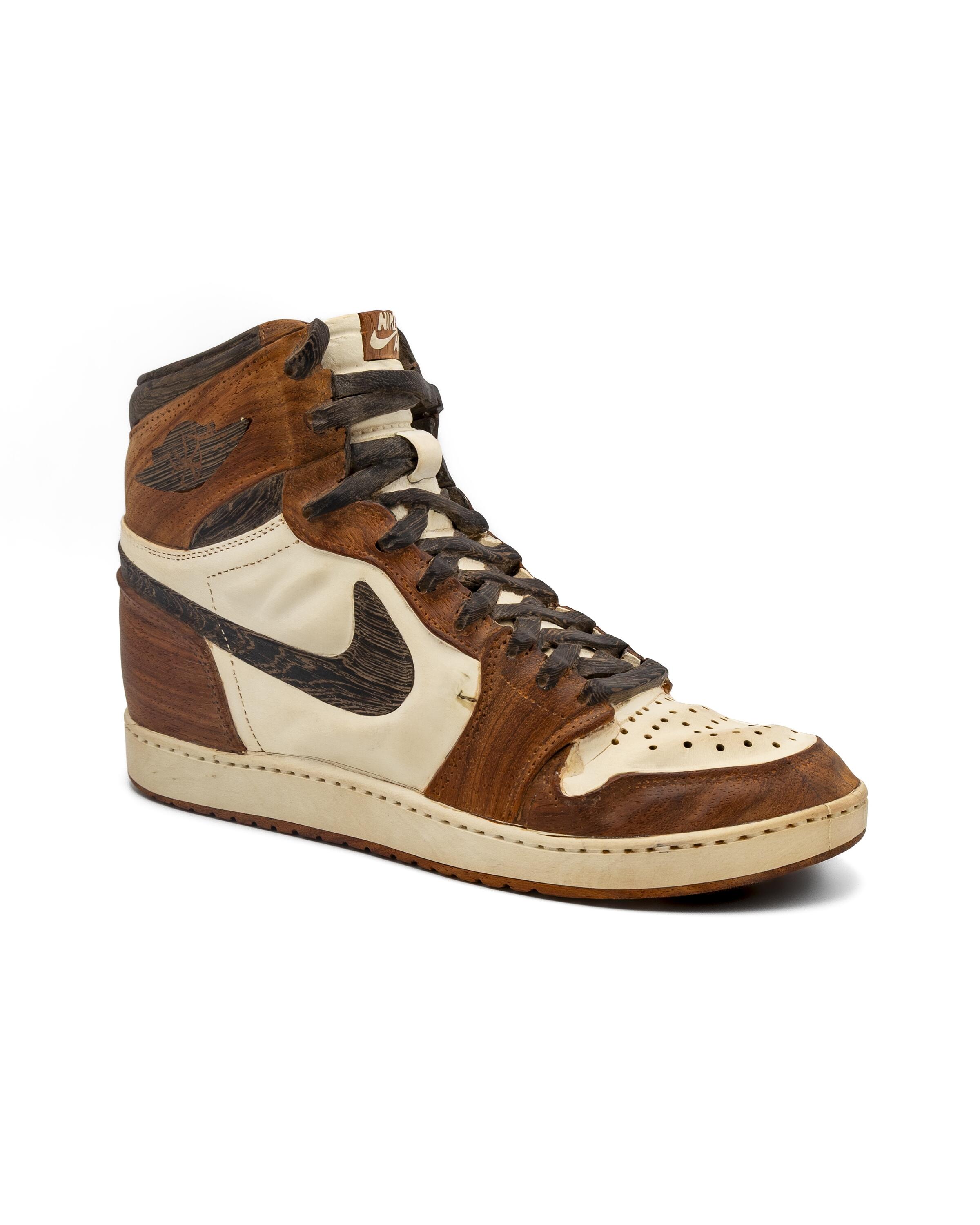 Two pairs of Nike Air Jordan 1 sneakers in boxes—one made of carved wood, the other a classic red, white, and black leather pair