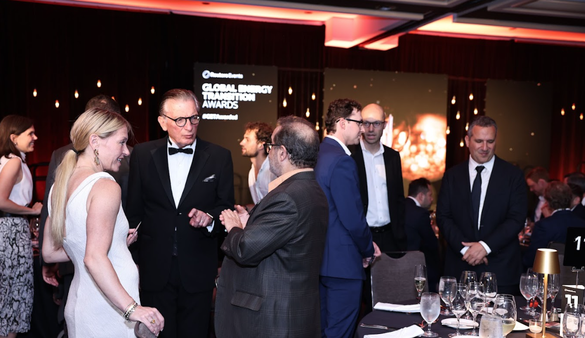 Guests networking at the Global Energy Transition Awards dinner, standing and talking around tables in a dimly lit ballroom.