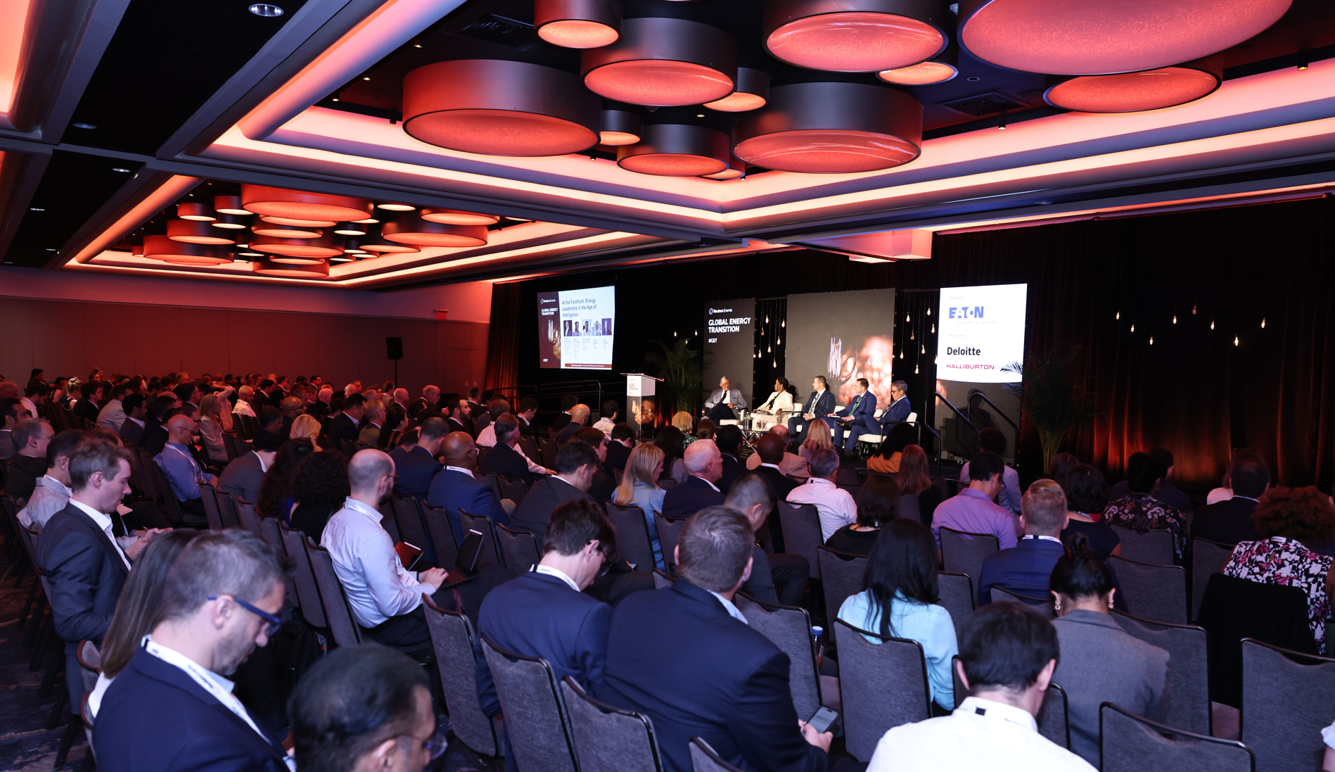 Full audience watches five‑person panel at an energy conference.