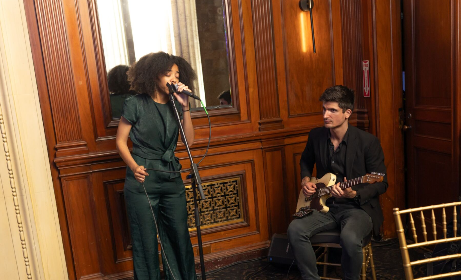Singer performing with a guitarist at an indoor event.