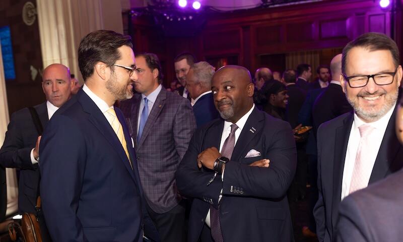 Guests in suits networking and talking at an evening reception.