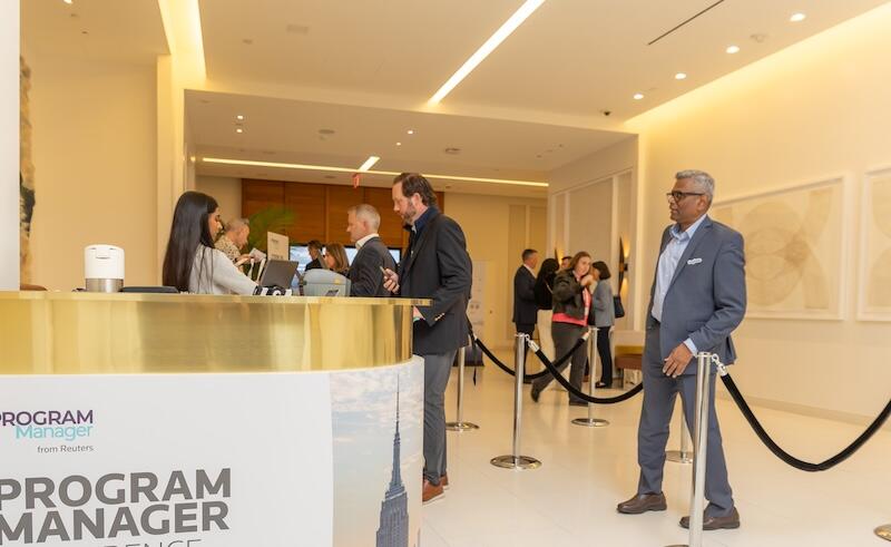 Attendees checking in at a modern conference registration desk in a bright lobby.