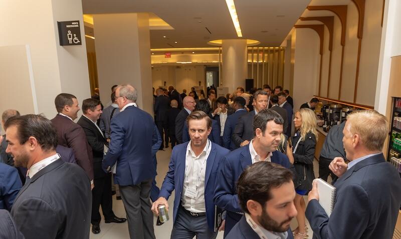 Attendees networking and talking in a crowded conference hallway.