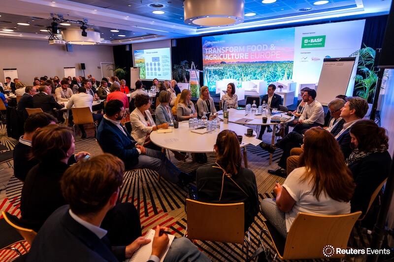 A photo of the a ground round table discsuion at a Transform Food & Agriculture event of people listening to a presentation 