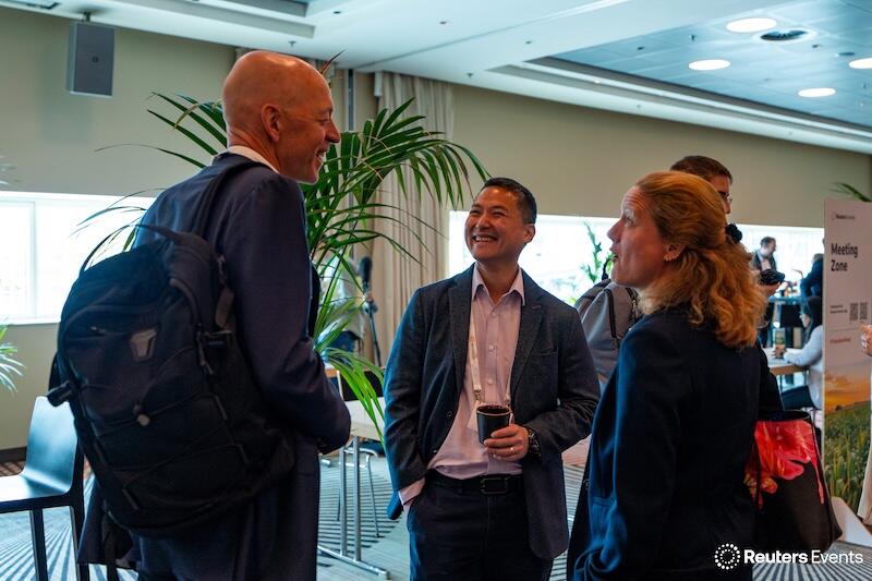 Three attendees enthusiastically exchanging ideas at a booth, smiling