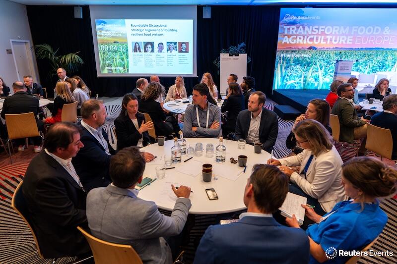 A photo of the a ground round table discsuion at a Transform Food & Agriculture event of people listening to a presentation 