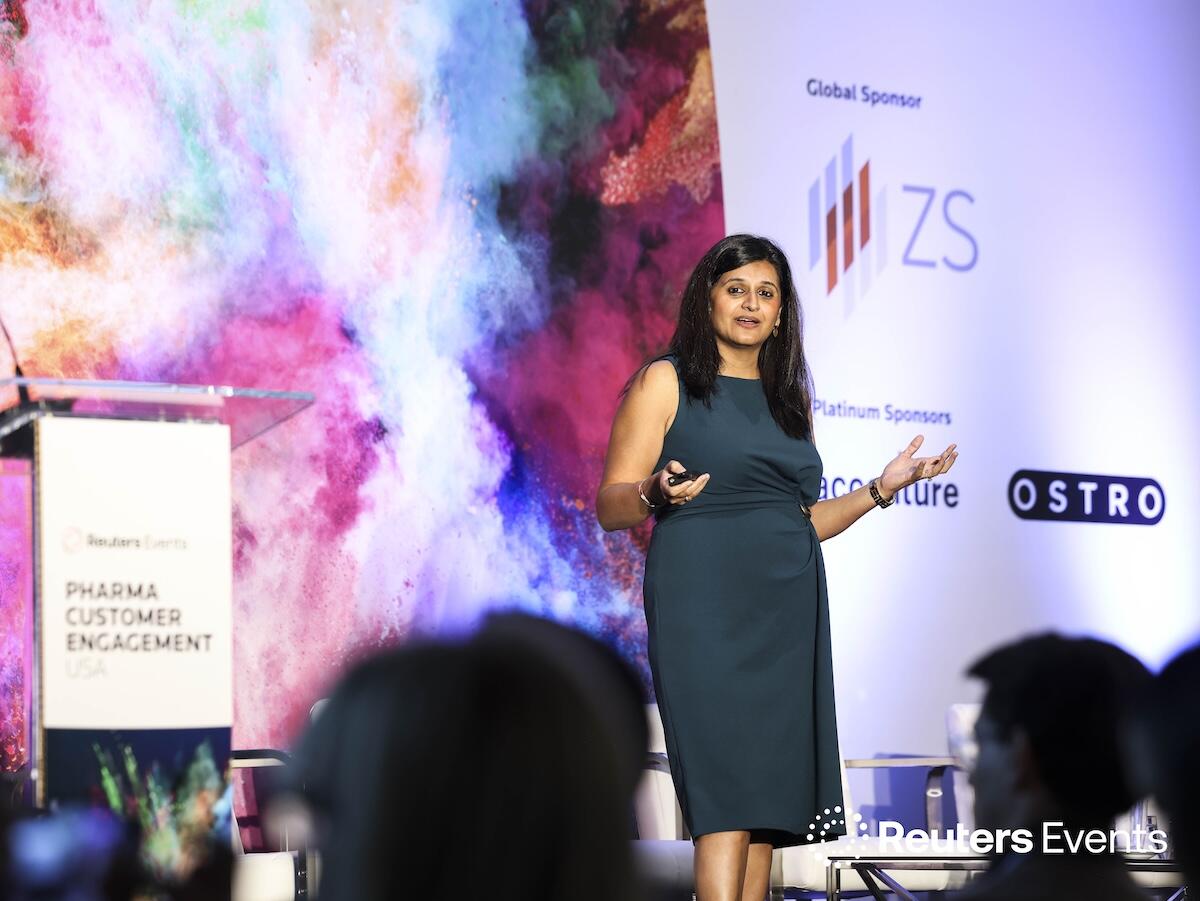 Speaker gesturing onstage at Pharma Customer Engagement USA