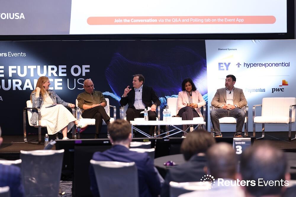 Photo of 5 speakers on stage giving a panel presentation at the The Future of Insurance USA event
