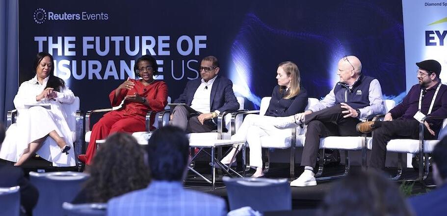 Photo of 6 speakers on stage giving a panel presentation at the The Future of Insurance USA event
