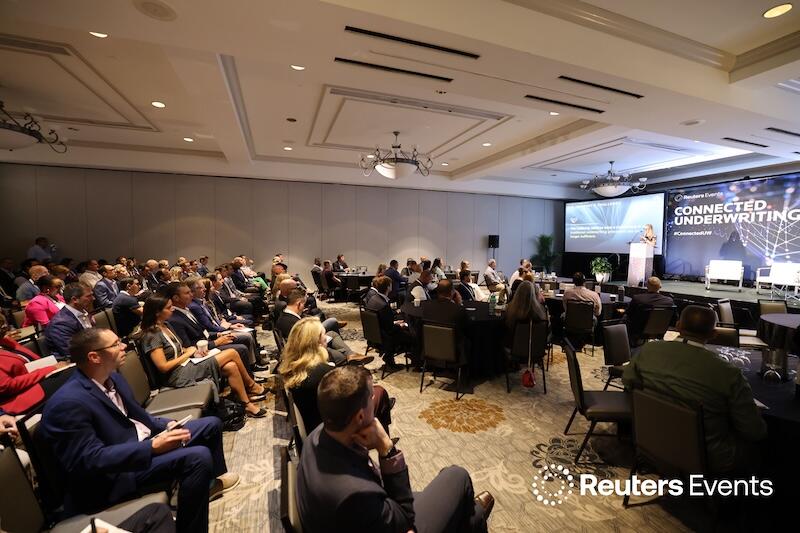 A room full of people watching a presentaion at  Connected Underwriting USA