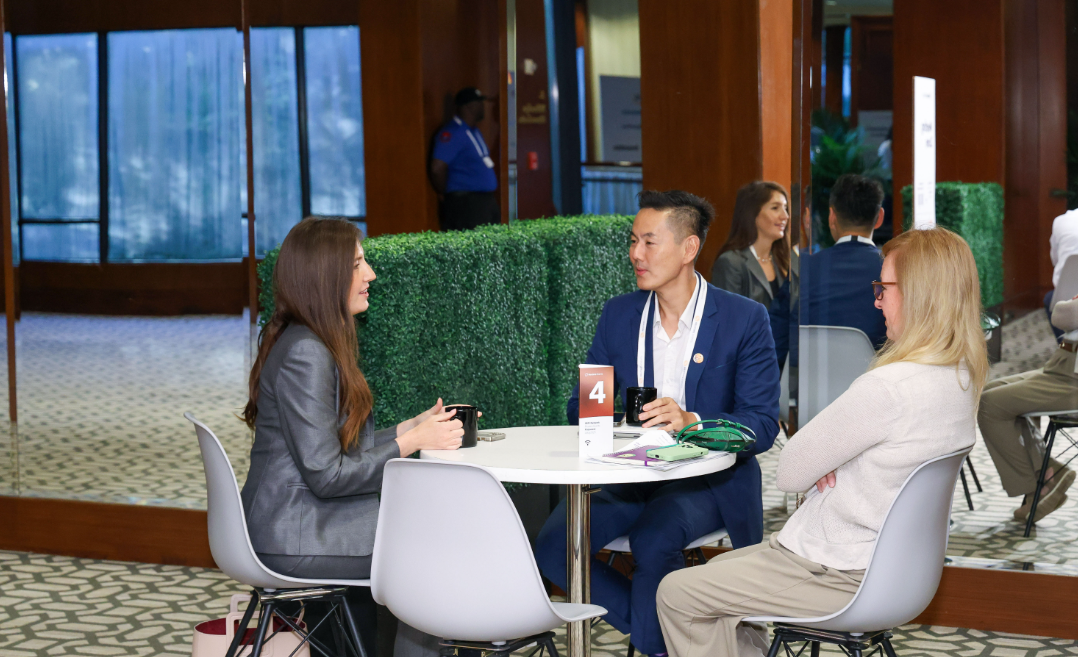 Three professionals talking around a small table during a business networking event.