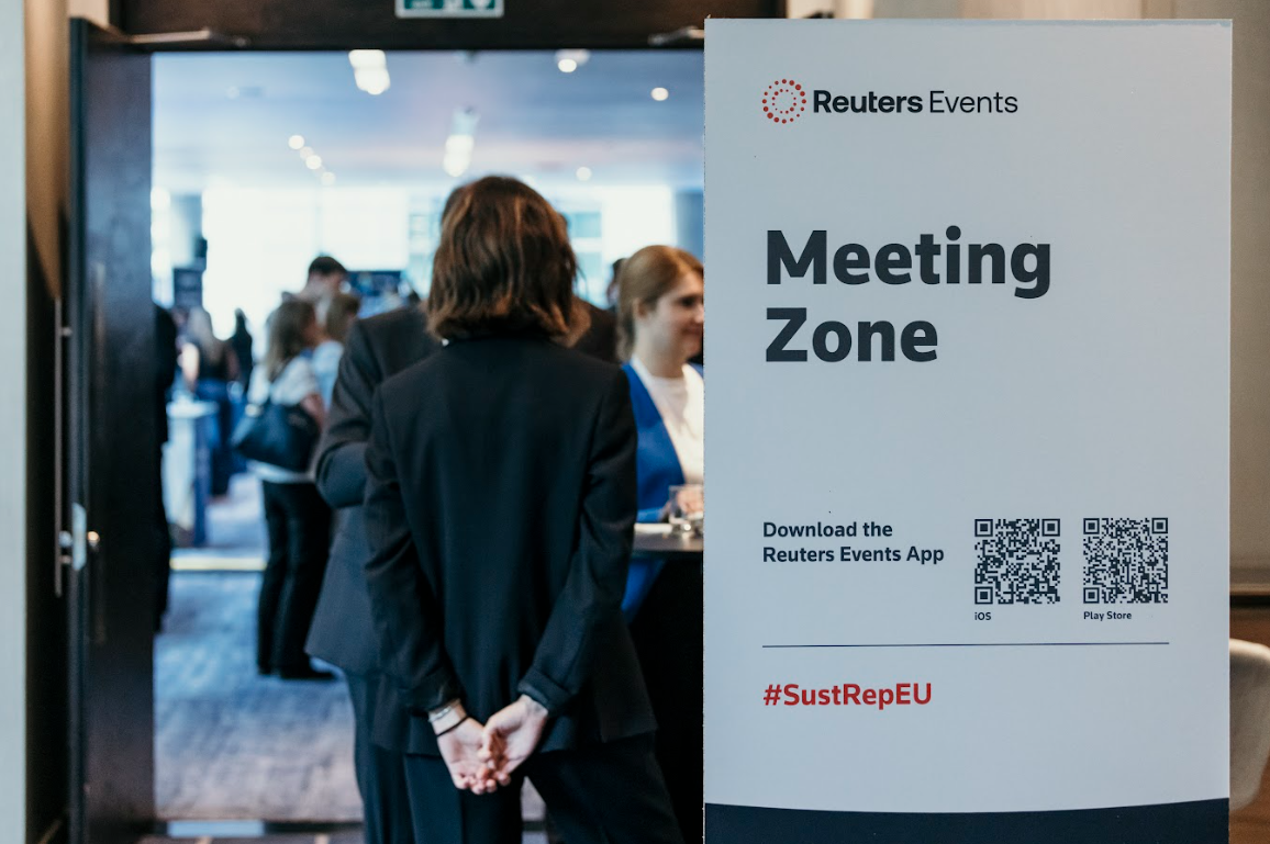 Conference attendees networking beside "Meeting Zone" sign