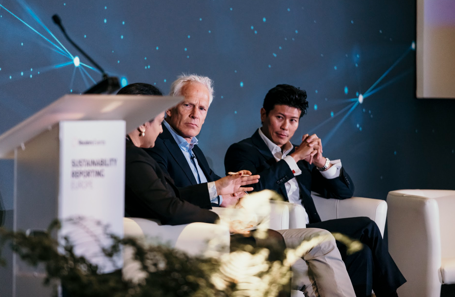 Three panelists seated on stage during conference discussion