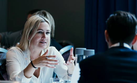 Woman speaking with another attendee at conference table