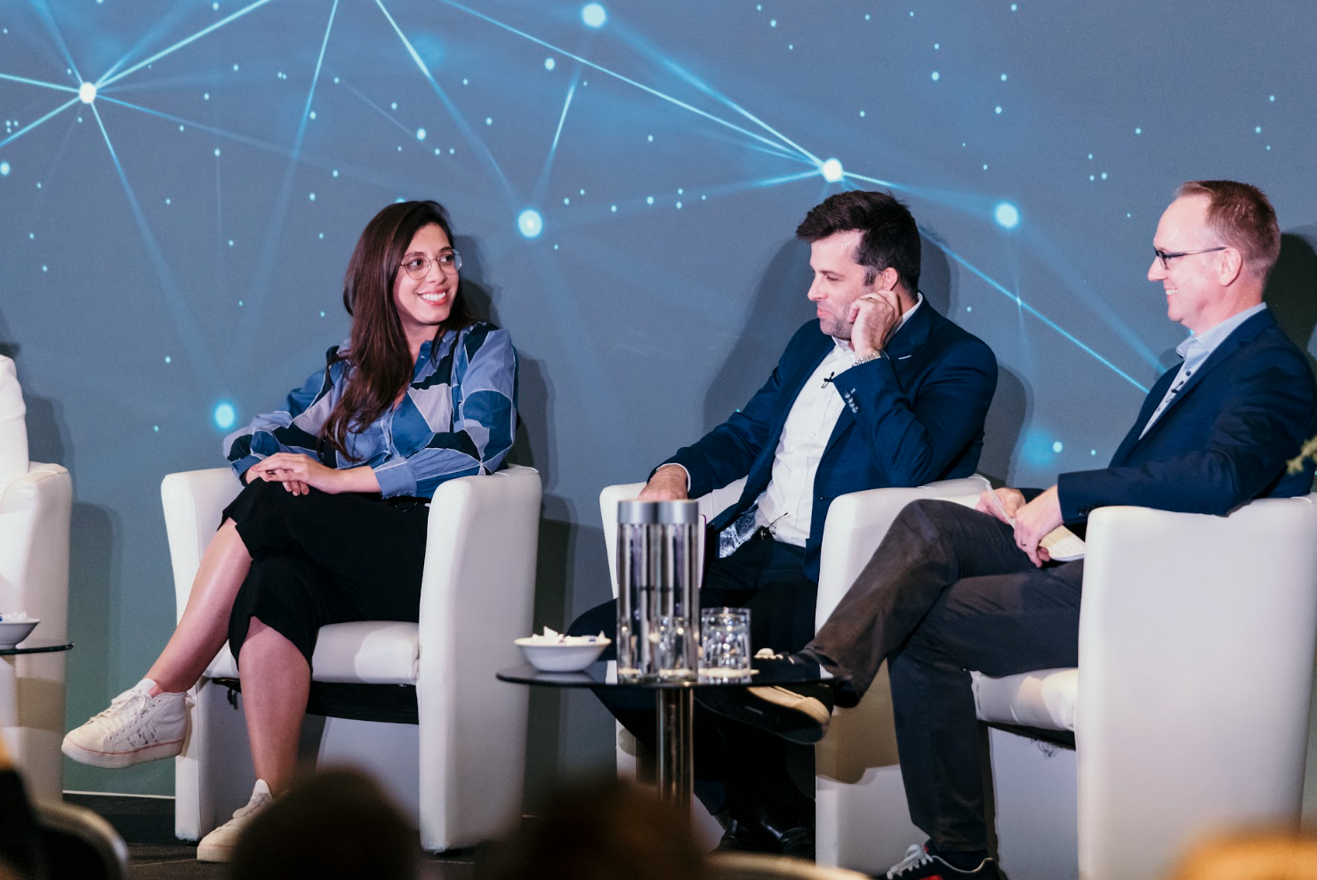 Three panelists seated on stage during conference discussion