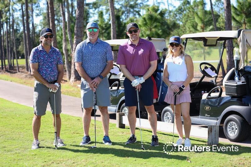 A photo of a group of people in golf clothing posing in front of gold buggies at the Connected Claims USA conference