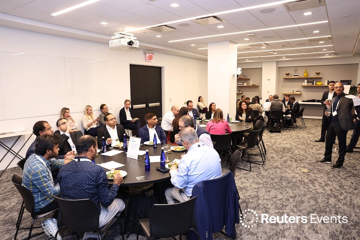 A photo of the  a presentator taliking to a group of people at roundtables  at the Momentum AI Finance USA Event