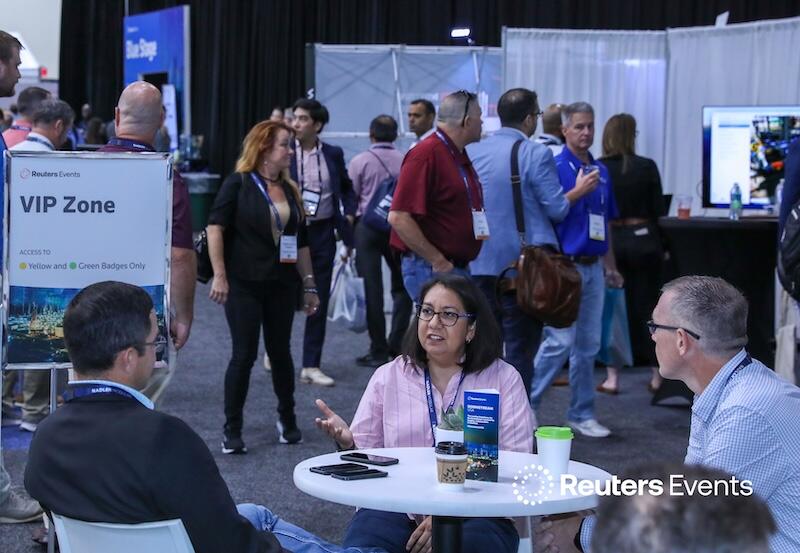 A group of people talking and others walking around expo booths