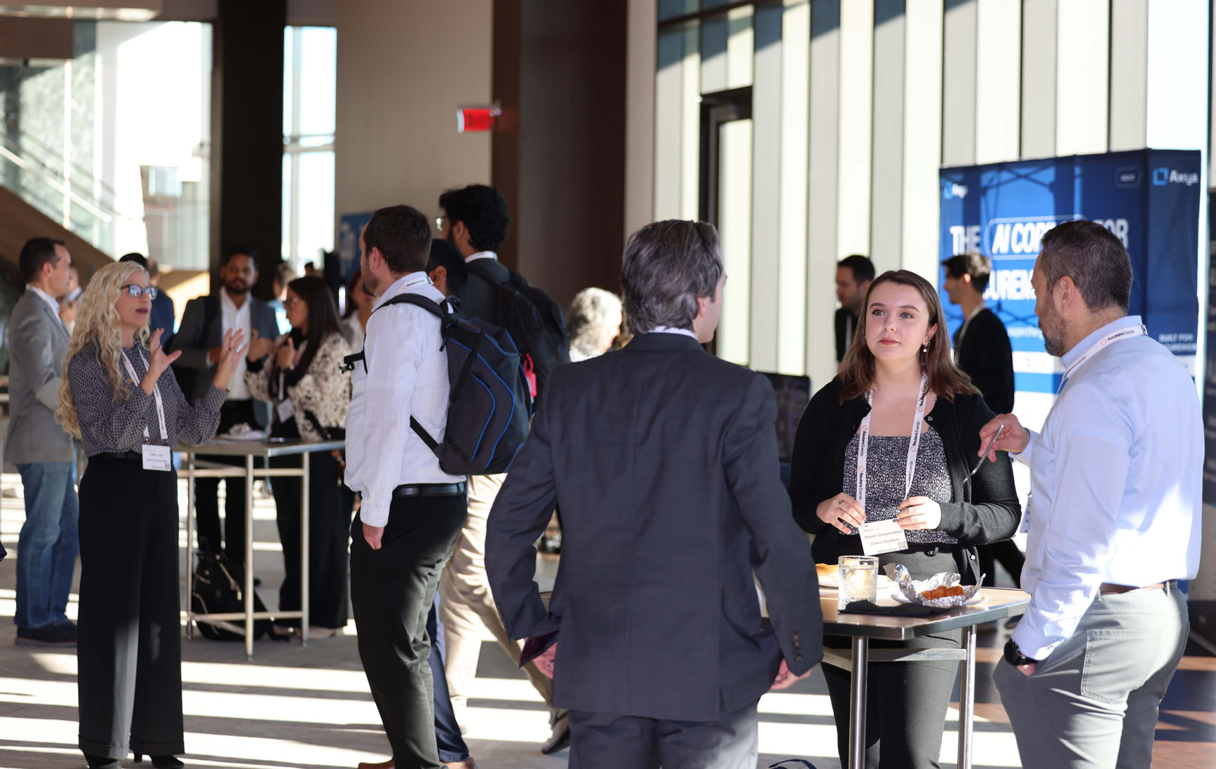 Conference attendees networking in a sunlit lobby.