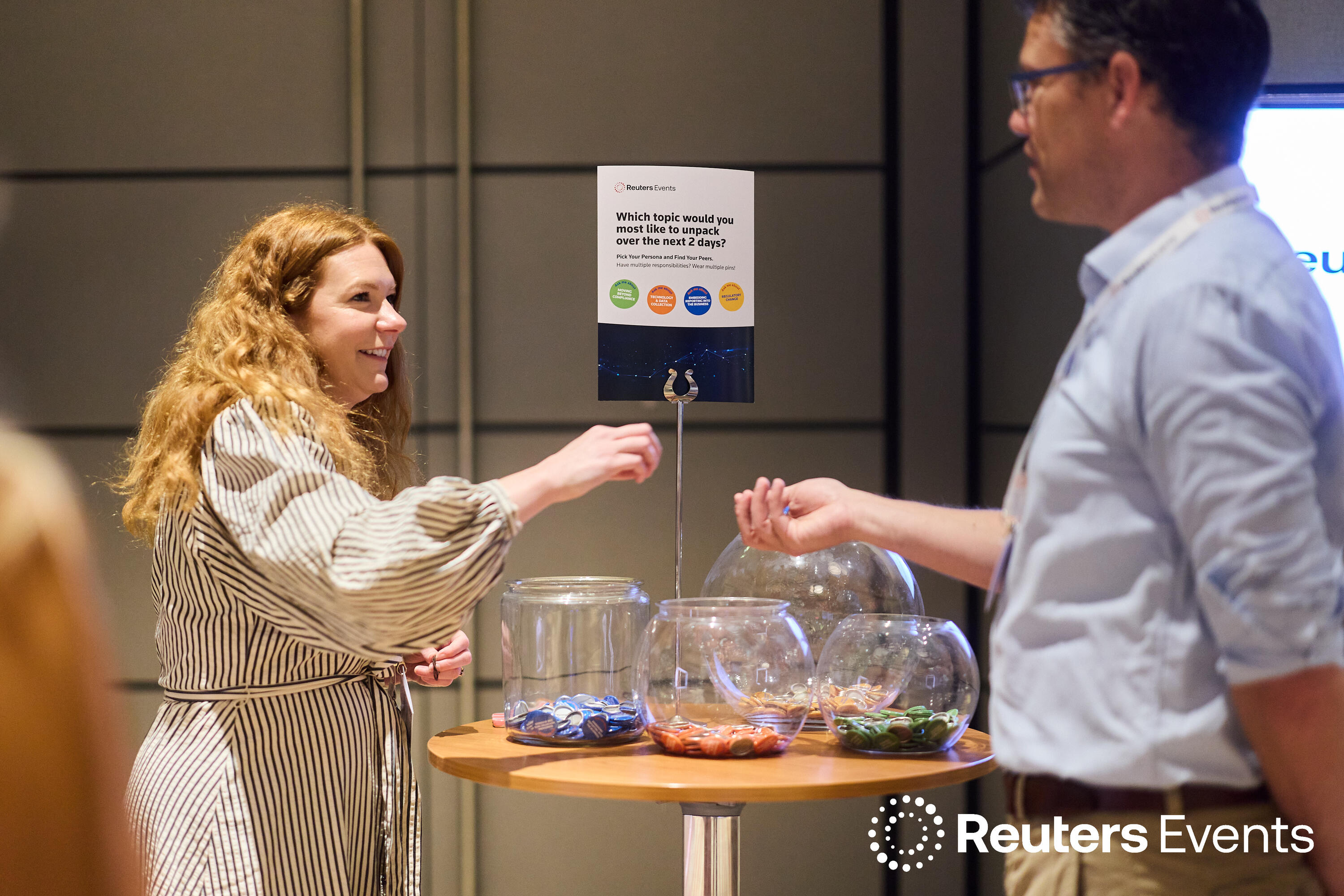 A smiling attendee engages with a Reuters Events interactive topic-selection activity at the Sustainability Europe conference.