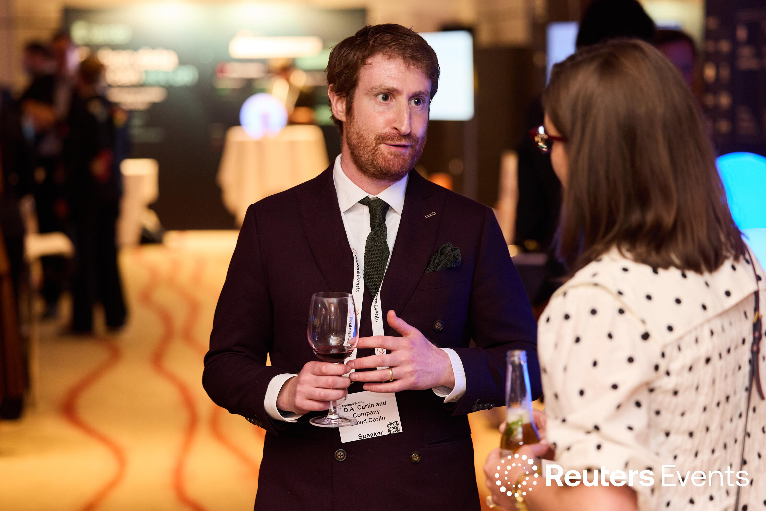 Speaker David Carlin of D.A. Carlin and Company holds a glass of wine while in conversation at a Reuters Events Sustainability Europe networking reception.