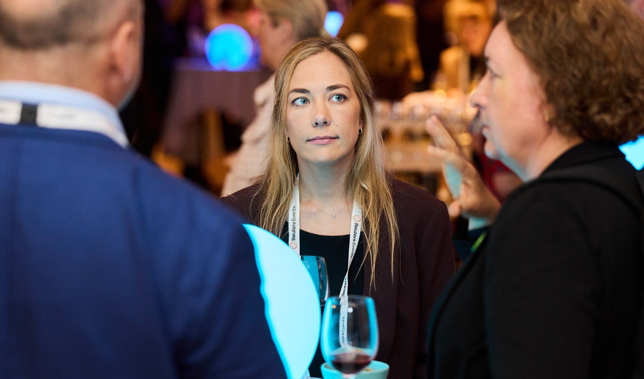 A female attendee wearing a Reuters Events lanyard listens attentively during a networking reception at Sustainability Europe.