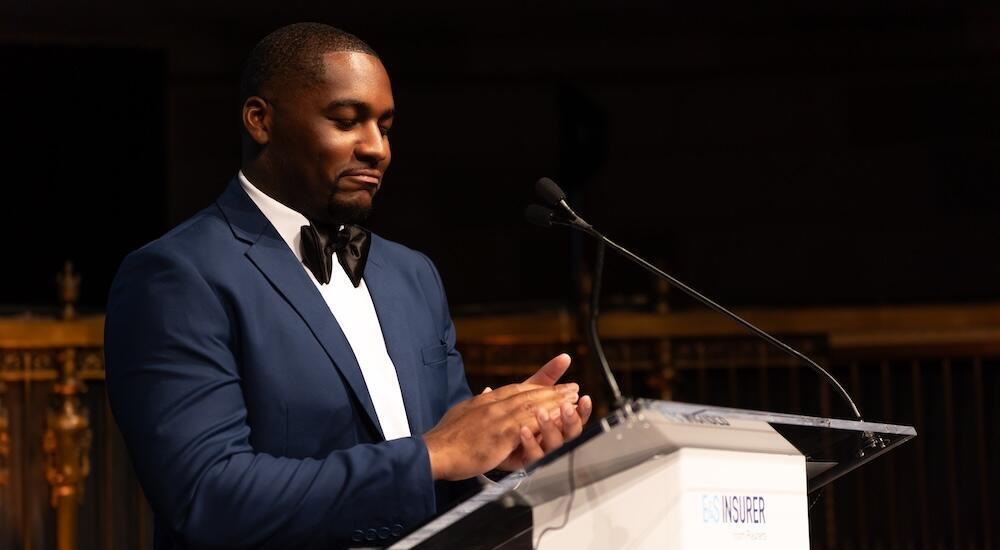 Presenter on stage at a podium clapping
