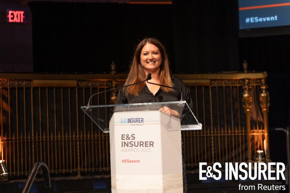 Presenter on stage at a podium smiling