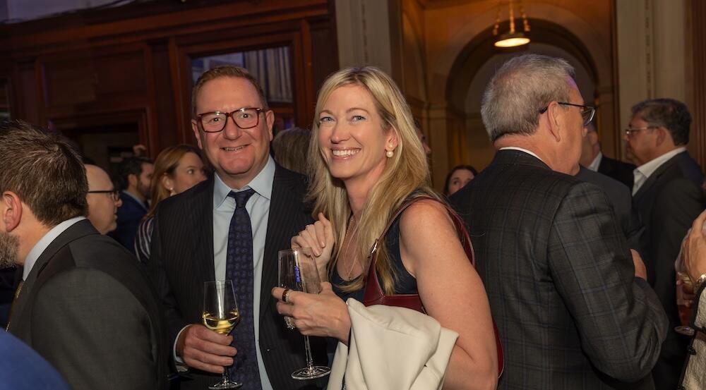 Two people holding drinks, smiling at the camera