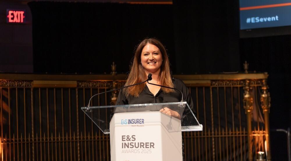 Presenter on stage at a podium smiling