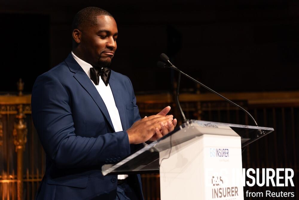Presenter on stage at a podium clapping