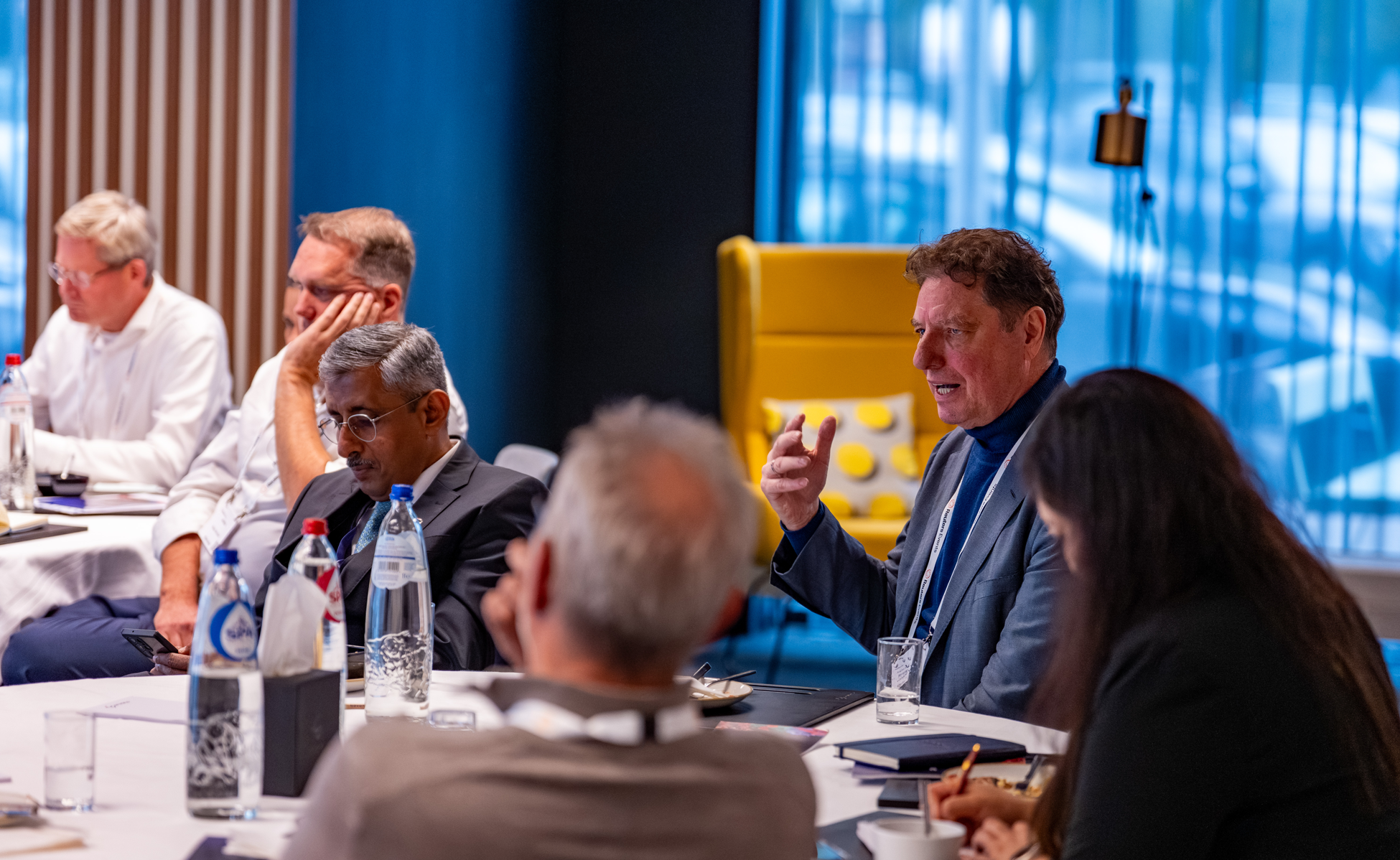 Attendees seated around a table during a conference discussion.