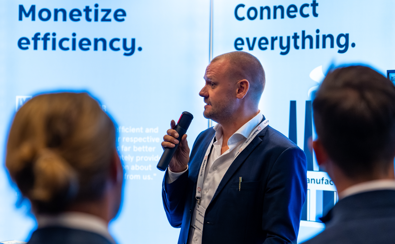 Man speaking into a microphone at an expo booth.