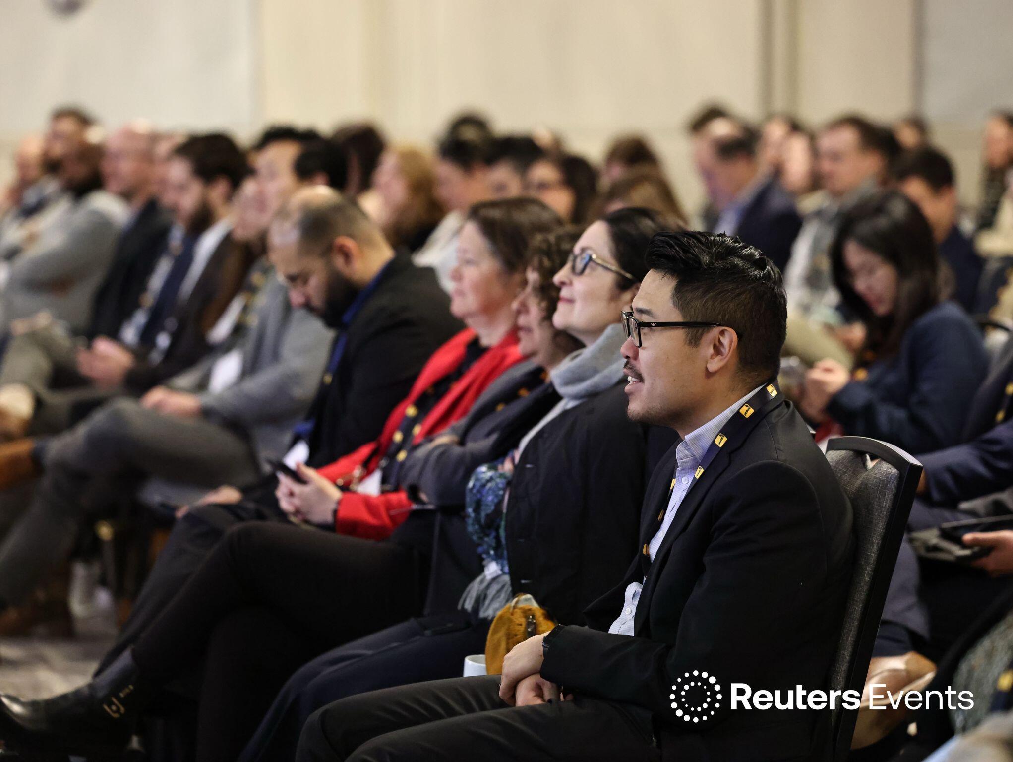 A room full of people seated watching a presentation