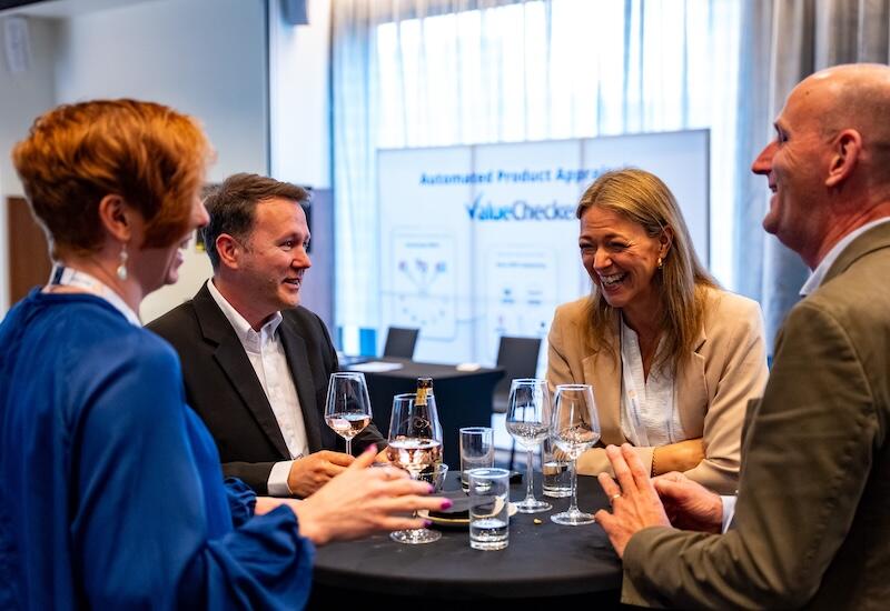 People networking with glasses of wine at a standing table
