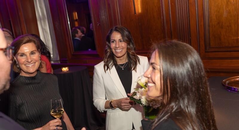 Four people chatting holding drinks smiling