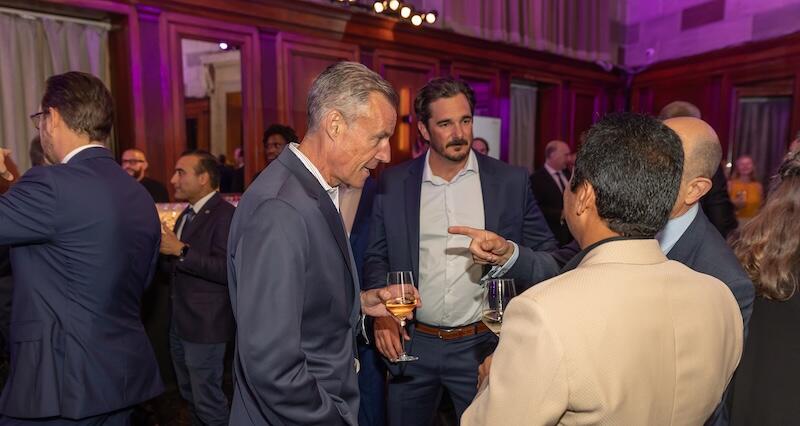 Four people taking together holding drinks