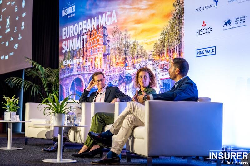 Three speakers sitting in white chairs on stage at the European MGA summit last year. 