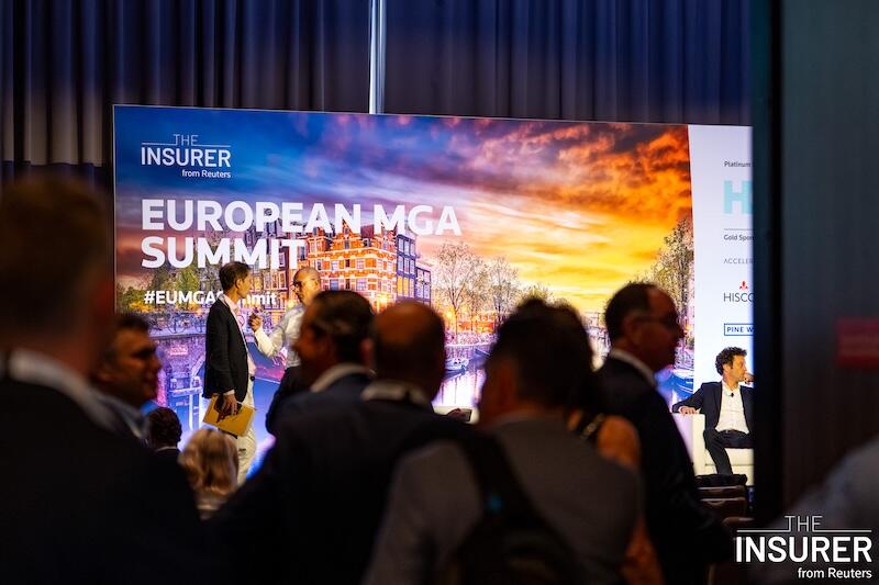 A photo of people talking in front of a large screen at an event