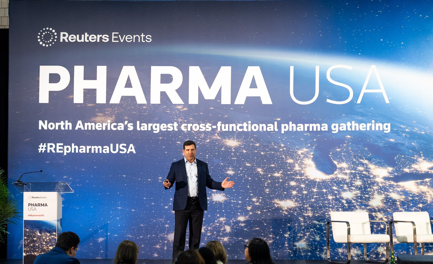 Speaker onstage at Pharma USA, mid-presentation