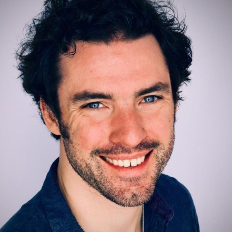 Headshot of Mark Reidy, a smiling man wearing a dark collared shirt