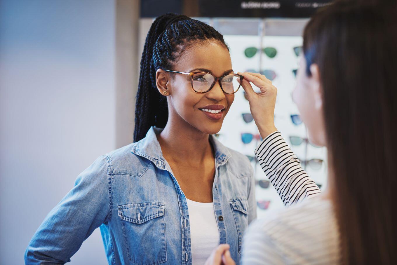 A woman trying on a pair of glasses with the assistance of an optician